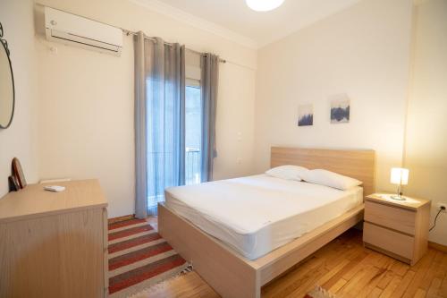 a white bedroom with a bed and a window at Ano Kipseli 2 bedrooms 4 pers apartment in Athens