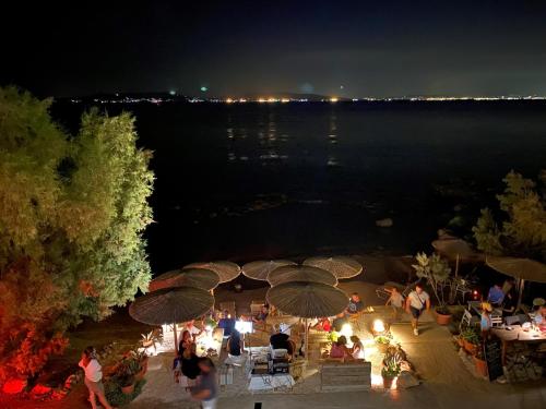 a group of people standing around tables with umbrellas at night at The Beachhouse Apartments in Vaia