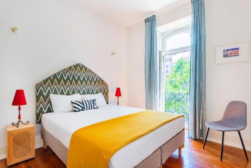 a bedroom with a bed and a window and a chair at Conde 3BDR Luxury in Lisbon