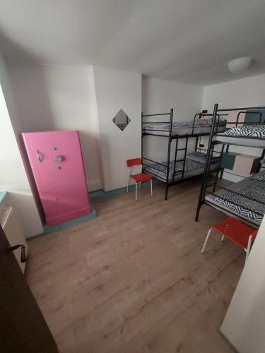 ブルノにあるSchrott Bed&Beerの二段ベッド2台とピンクのドアが備わる客室です。