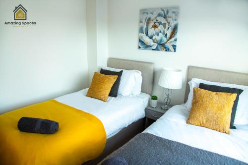 ウォリントンにあるCosy 2 Bed Flat Sleeps 4 with Free Parking by Amazing Spaces Relocations Ltdのベッドルーム1室(黄色い枕のベッド2台付)