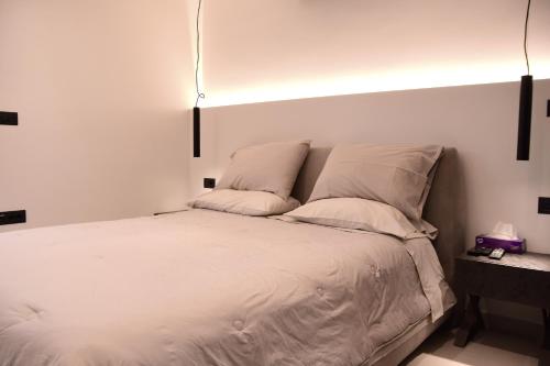 a bedroom with a white bed with two pillows at White and Black Aegina in Áyioi Asómatoi