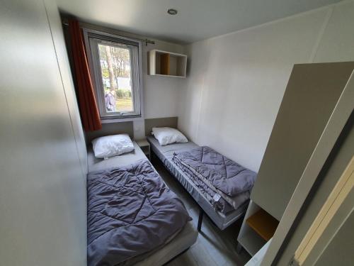 une petite chambre avec deux lits et une fenêtre dans l'établissement Smala, à Saint-Julien-en-Born