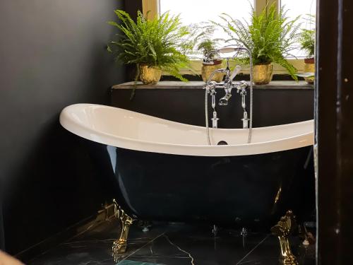 a bathroom with a black and white tub with potted plants at Alice in Spa