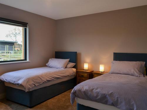 a bedroom with two beds and a window and two lamps at Brewers Cottage in Slaley