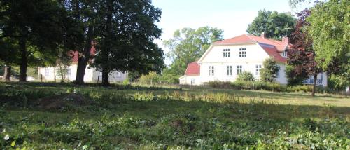 a white house with a red roof in a field at Yxkullsund Säteri B&B - Manor & Estate since 1662 in Lagan