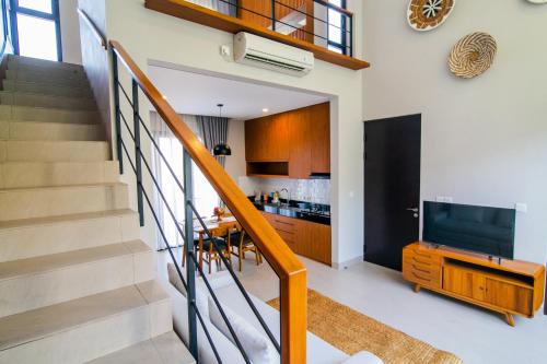 een woonkamer met een trap en een televisie bij De Hsahe Villas in Tanah Lot