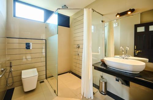 a bathroom with a sink and a glass shower at Thekkady Gavi Suites in Vandiperiyār