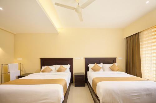 a bedroom with two beds and a window at Thekkady Gavi Suites in Vandiperiyār