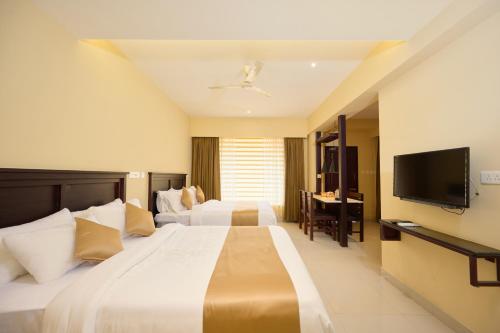 a hotel room with a large bed and a flat screen tv at Thekkady Gavi Suites in Vandiperiyār