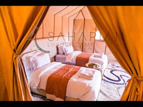 2 camas en una habitación con cortinas en Room in Bungalow - Saharian Luxury Camp, en Tisserdmine