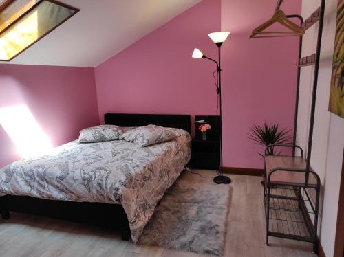 ein Schlafzimmer mit einem Bett und einer rosa Wand in der Unterkunft Chez Sam in Villebois