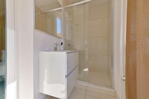 une salle de bain blanche avec un lavabo et une douche dans l'établissement Studio rénové Hyper Centre- Ajaccio, à Ajaccio