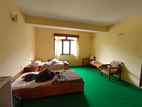 Habitación con 2 camas y alfombra verde. en Hotel Pemathang, en Pemayangtse