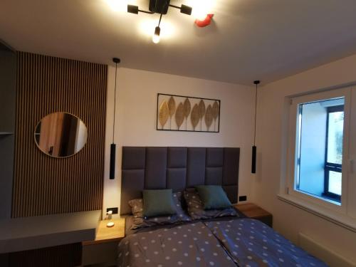 a bedroom with a bed and a mirror and a window at Apartman Dream Jahorina Snjezna Dolina in Jahorina