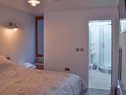 a bedroom with a bed and a bathroom with a shower at Chunal Apartment - Uk12958 in Glossop