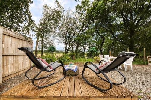 two chairs sitting on a wooden deck in a yard at Hayloft at Bonnyside House in Bonnybridge