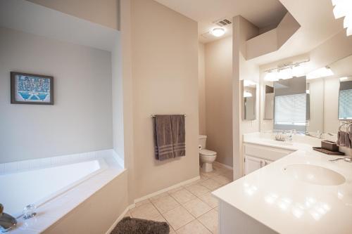 Baño blanco con bañera y lavamanos en Splendid House With Pool! en Las Vegas