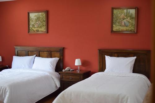two beds in a room with orange walls at Hotel Ambassador in Quito