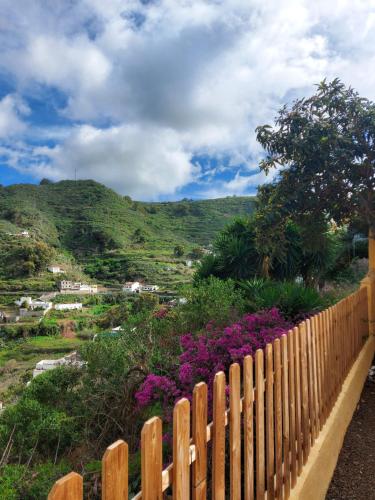 una valla de madera frente a una colina con flores en Casa Rebeca, en Teror