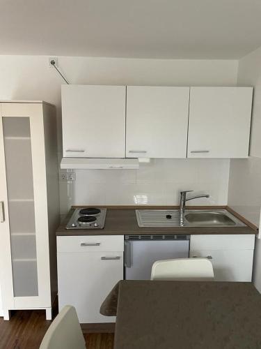 uma pequena cozinha com armários brancos e um lavatório em Z.Bilić V&V em Jesteburg