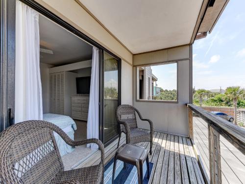 a balcony with two wicker chairs and a bed at Sea Matanzas 2 in Saint Augustine