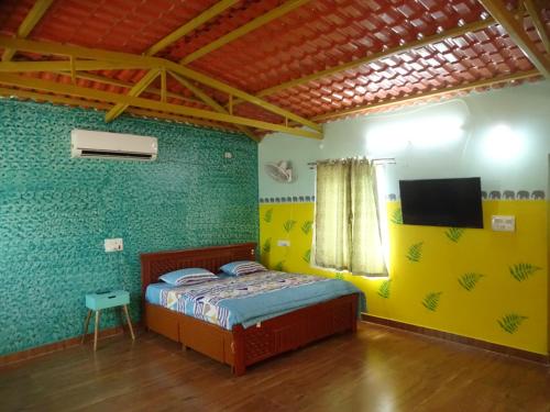 a bedroom with a bed and a tv in it at MangoHut Farmhouse Pool Villa in Hyderabad