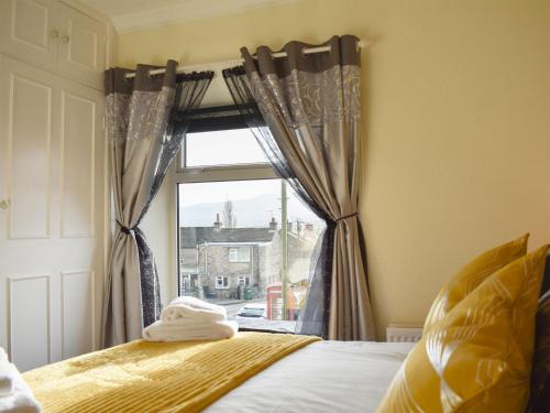 Un dormitorio con una ventana con cortinas y una cama en Grassgarth Cottage, en Redmire