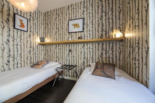 two beds in a room with black and white wallpaper at L'Eau Vive Jacuzzi et Sauna en vieille ville 5 in Annecy