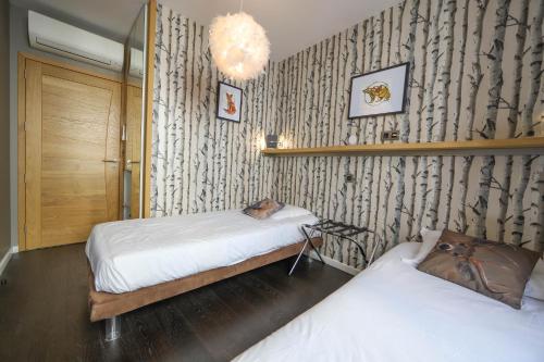 a bedroom with two beds and a wall with wallpaper at L'Eau Vive Jacuzzi et Sauna en vieille ville 5 in Annecy