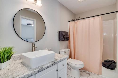 bagno bianco con lavandino e specchio di The Masters Cottage by Augusta National ad Augusta