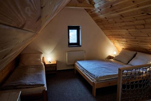 a attic room with two beds and a window at Apartmány Pod Stráni in Malá Morávka
