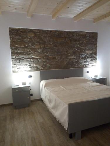 Agriturismo Campo Luente في Rocchetta di Vara: غرفة نوم بسرير وجدار حجري
