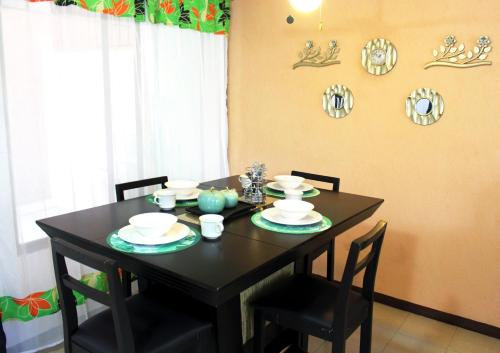 a black dining room table with chairs and plates on it at Casa Palmera con Aire acondicionado Alberca Wifi cocina y TV in Emiliano Zapata