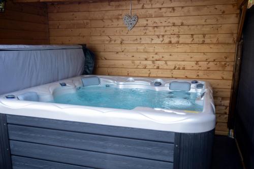 bañera de hidromasaje en una habitación con pared de madera en Thudi-nids en bulles, en Gozée