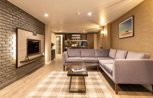 uma sala de estar com um sofá e uma parede de tijolos em The Lawrance Luxury Aparthotel - York em York