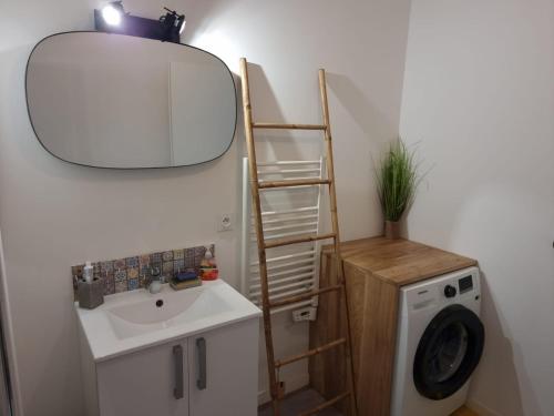 y baño con lavabo, espejo y lavadora. en Appartement nouveaux quartier Bologne à deux pas de Mosson, WiFi, climatisation et parking gratuit en Montpellier