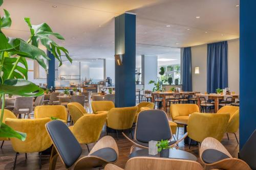 a restaurant with yellow chairs and tables at Hotel Oberhausen Neue Mitte affiliated by Meliá in Oberhausen