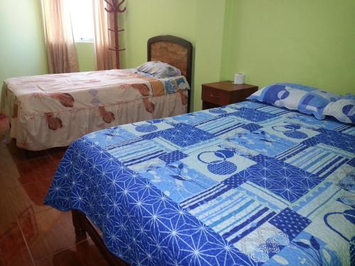 a bedroom with two beds with a blue and white quilt at Hostal Puerto Ingles in Ilo