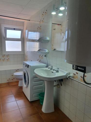 a bathroom with a sink and a washing machine at Payet Apartments in L'Estartit