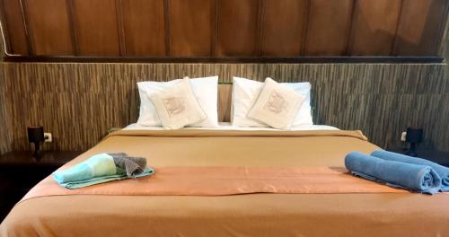 Una cama en una habitación de hotel con dos toallas. en Meno Turtle BUNGALOWS, en Gili Meno