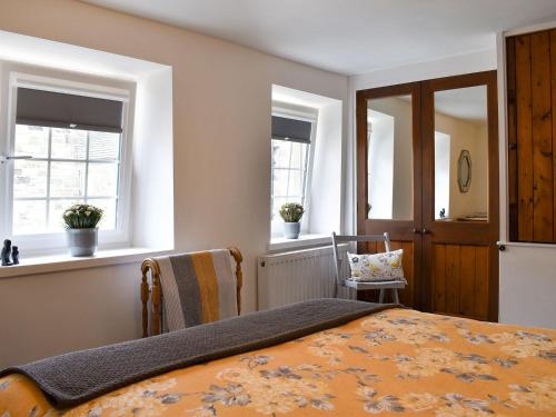 a bedroom with a bed and two windows at Beckside Cottage in Silsden