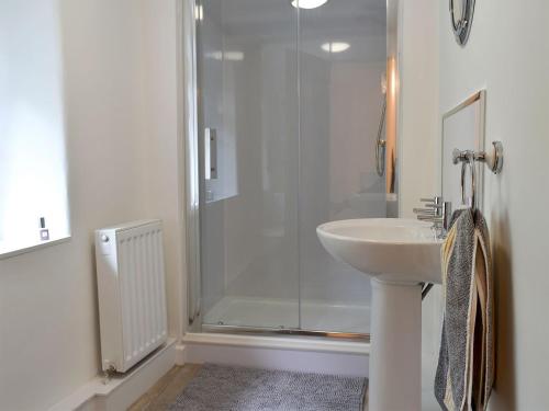a white bathroom with a shower and a sink at Beckside Cottage in Silsden