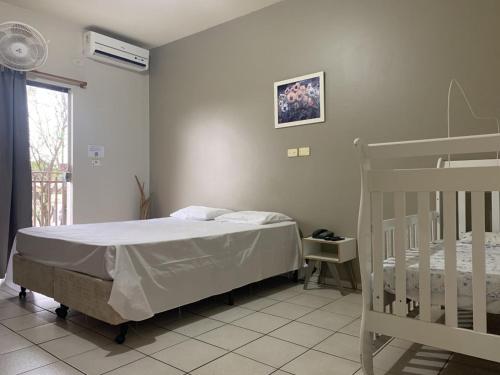 a bedroom with a bed and a crib at Ouro Hotel in Ourinhos
