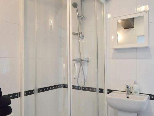 a white bathroom with a shower and a sink at Weavers Houses in Hayfield