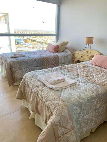 2 camas en una habitación con ventana en Los Cardos Suites en Neuquén