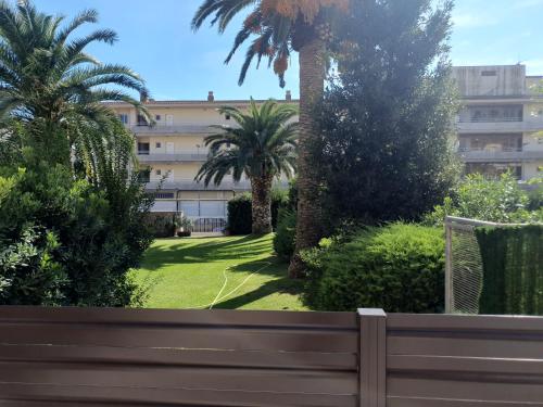 a park with a bench and palm trees and a building at Payet Apartments in L'Estartit