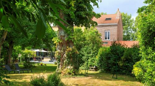 un parc avec un arbre et un bâtiment dans l'établissement Les Berges, à Bourbourg