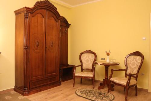 a room with a wooden cabinet and two chairs and a table at Hotel Astoria in Satu Mare