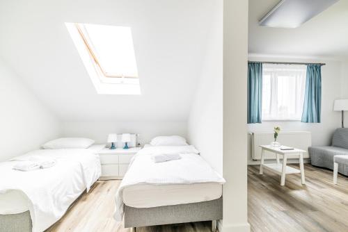 a white bedroom with two beds and a chair at EXPO HOSTEL in Kielce